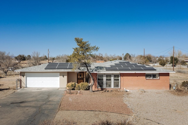 view of front of house with aphalt driveway, solar panels, brick siding, and a garage