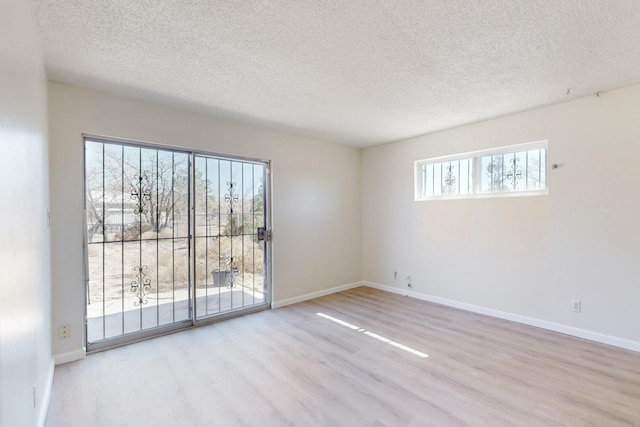 spare room featuring a textured ceiling, baseboards, and wood finished floors