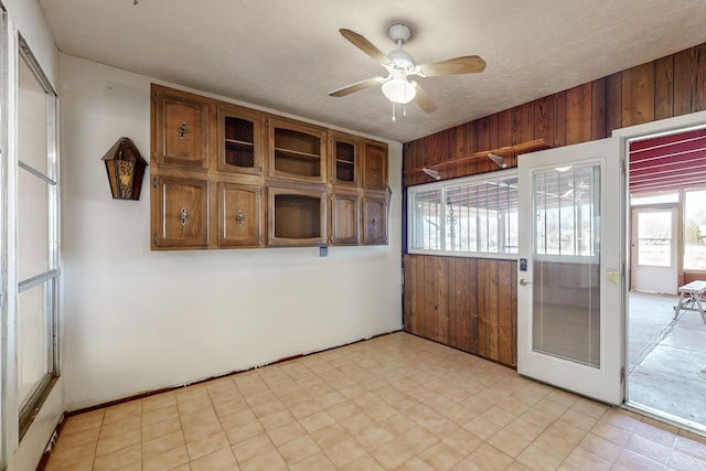 empty room featuring wooden walls, ceiling fan, and a textured ceiling