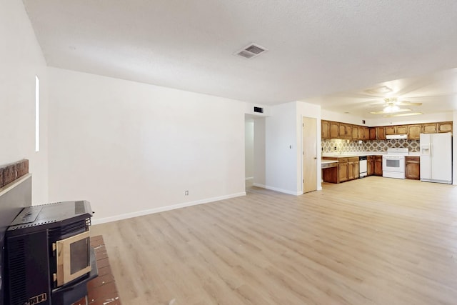 unfurnished living room with light wood finished floors, visible vents, baseboards, and a ceiling fan