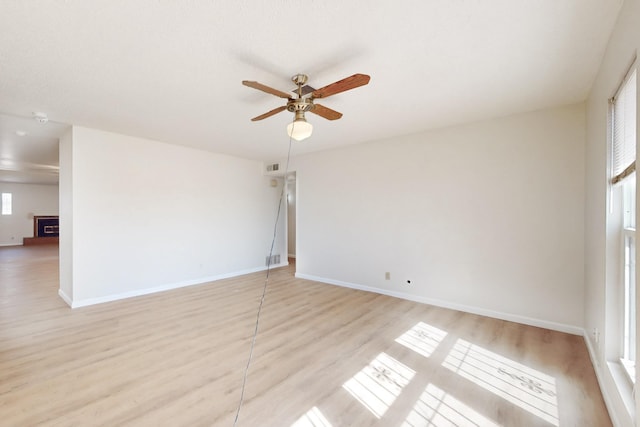 spare room with light wood-style flooring, baseboards, visible vents, and ceiling fan