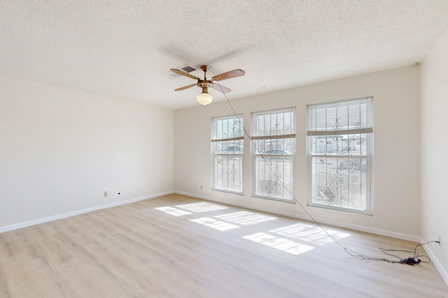 spare room with a textured ceiling, baseboards, a ceiling fan, and wood finished floors