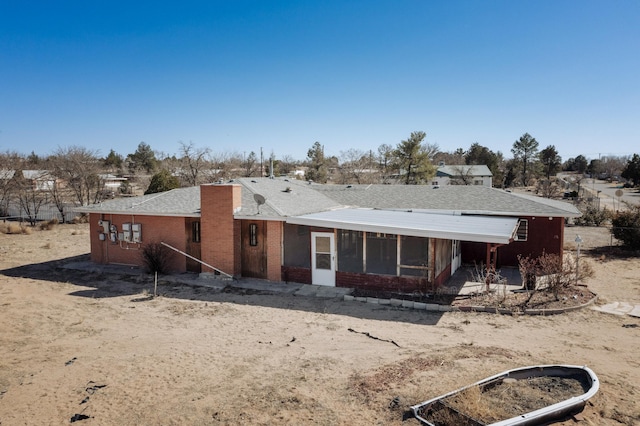 back of house with brick siding and roof with shingles