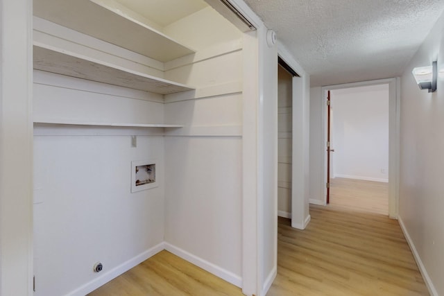 laundry area with light wood finished floors, baseboards, washer hookup, laundry area, and a textured ceiling