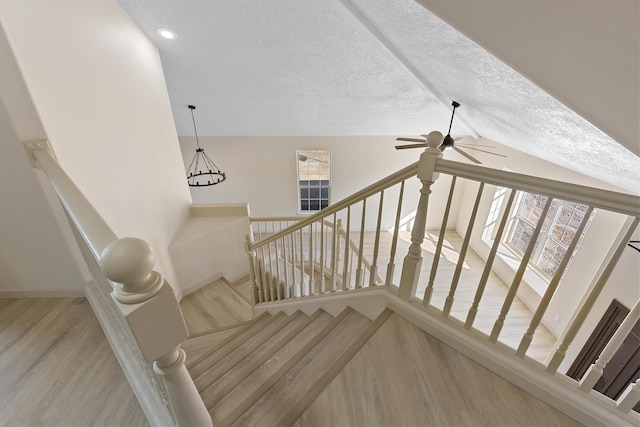 stairs featuring a textured ceiling, lofted ceiling, and wood finished floors