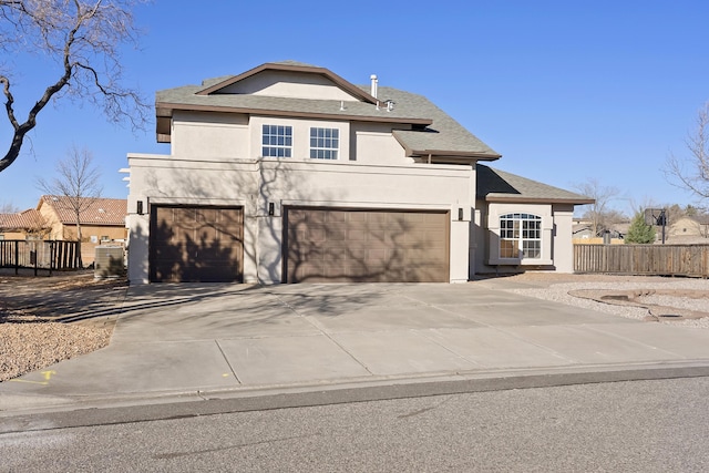 view of front facade with an attached garage, fence, driveway, and stucco siding