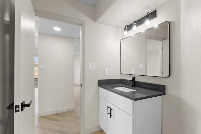 bathroom with baseboards, wood finished floors, and vanity