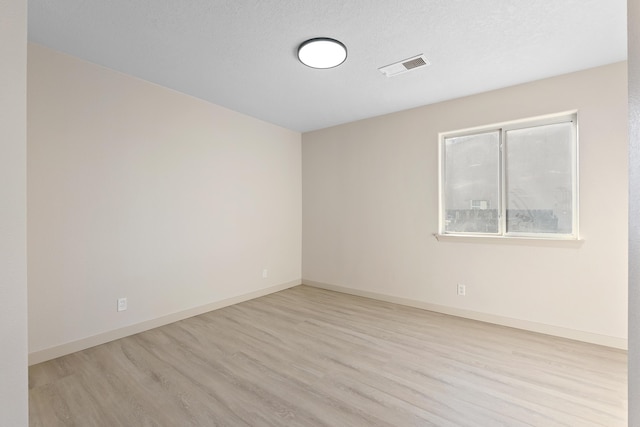 spare room featuring visible vents, wood finished floors, baseboards, and a textured ceiling