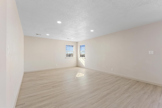 empty room with recessed lighting, baseboards, a textured ceiling, and light wood-style flooring