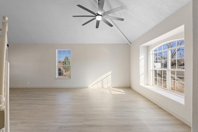 unfurnished room featuring lofted ceiling, a ceiling fan, a textured ceiling, wood finished floors, and baseboards