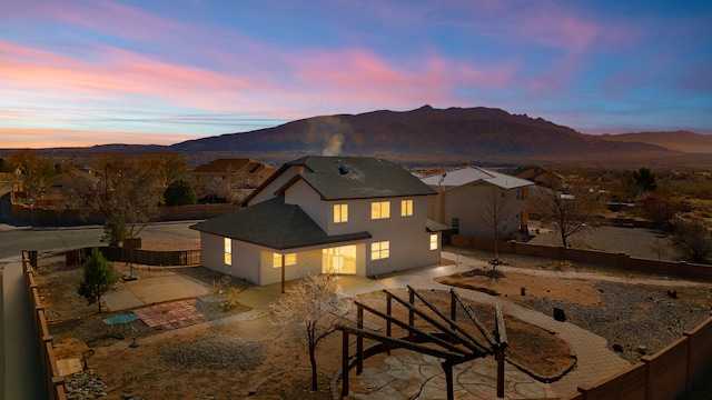 rear view of property featuring a patio area, a mountain view, a fenced backyard, and stucco siding