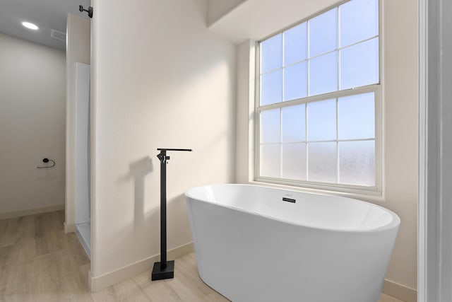 full bathroom with a freestanding tub, baseboards, visible vents, and wood finished floors