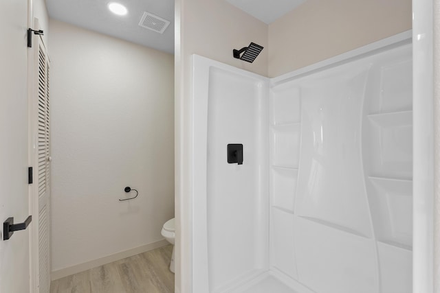 bathroom featuring wood finished floors, baseboards, visible vents, walk in shower, and toilet