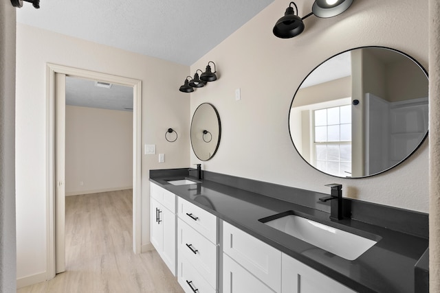 bathroom with a sink, a textured ceiling, and wood finished floors