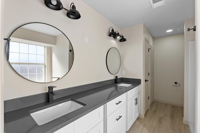 bathroom featuring double vanity, visible vents, wood finished floors, and a sink