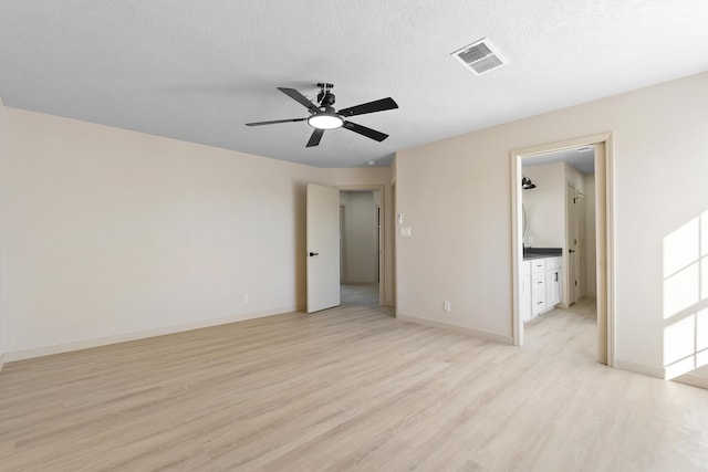 unfurnished bedroom featuring visible vents, light wood-style flooring, a textured ceiling, and baseboards