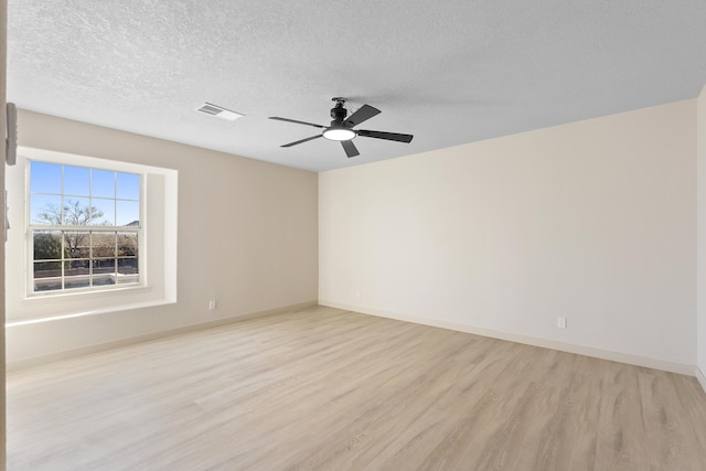 unfurnished room with baseboards, a textured ceiling, and light wood-style flooring