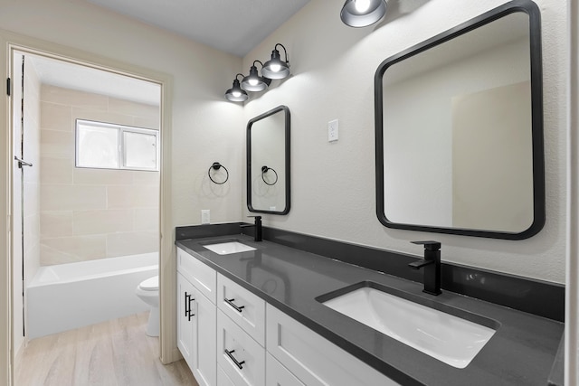 bathroom with double vanity, toilet, wood finished floors, and a sink