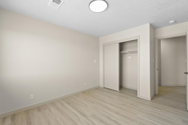 unfurnished bedroom featuring visible vents, light wood-style flooring, a textured ceiling, a closet, and baseboards