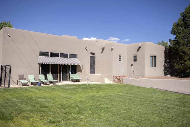 rear view of house with a yard, a patio, and stucco siding