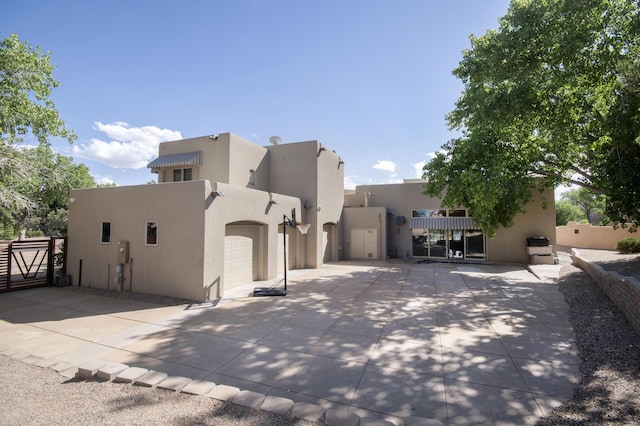 view of front facade featuring stucco siding, driveway, a garage, and fence