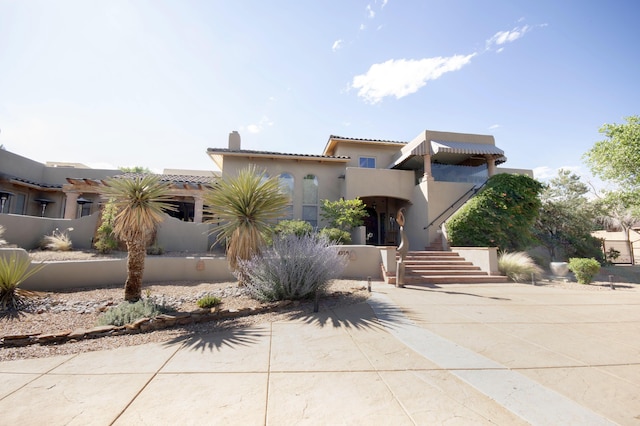 view of front of house with stucco siding, a tiled roof, and a chimney