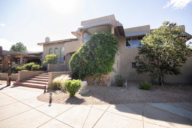 view of front of home featuring stucco siding, stairway, and a tiled roof