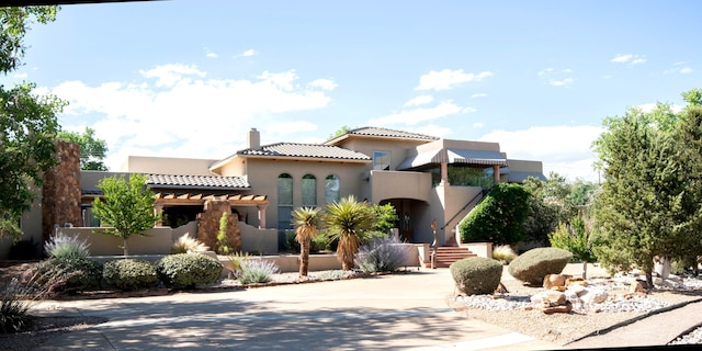 mediterranean / spanish house featuring a chimney, stucco siding, a tiled roof, and concrete driveway