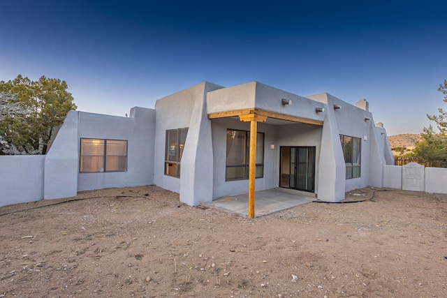 rear view of property featuring stucco siding, a patio, and fence