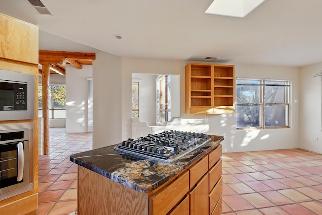 kitchen with light tile patterned floors, visible vents, a skylight, appliances with stainless steel finishes, and a glass covered fireplace