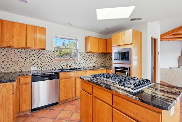 kitchen with visible vents, a sink, backsplash, stainless steel appliances, and a skylight