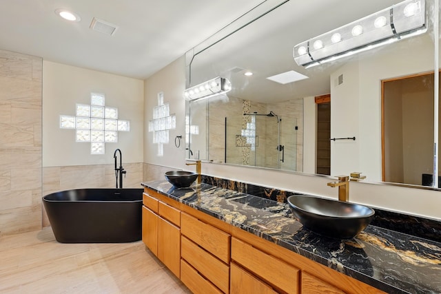 full bath featuring a sink, visible vents, tile walls, and a shower stall