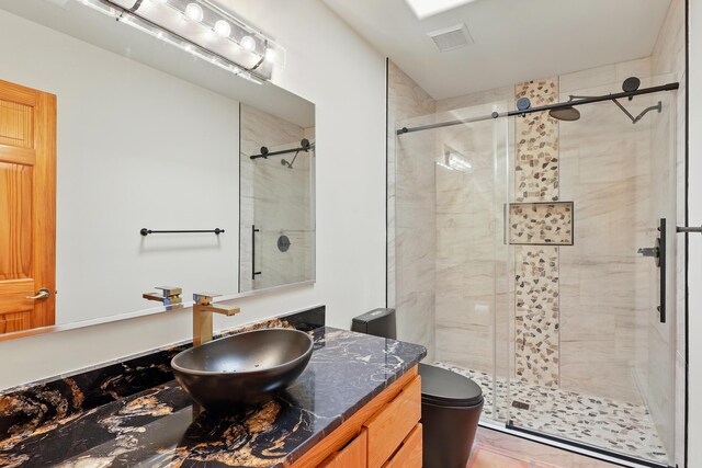 bathroom featuring visible vents, toilet, a stall shower, and vanity