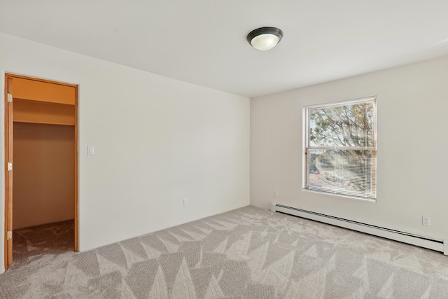 unfurnished bedroom with carpet flooring, baseboard heating, and a spacious closet