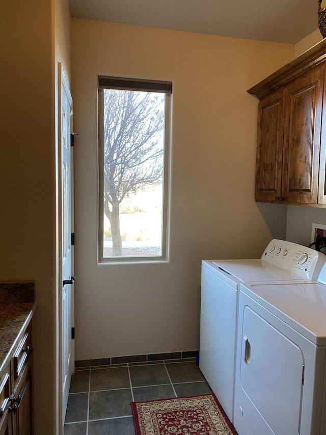 clothes washing area with baseboards, cabinet space, separate washer and dryer, and dark tile patterned flooring