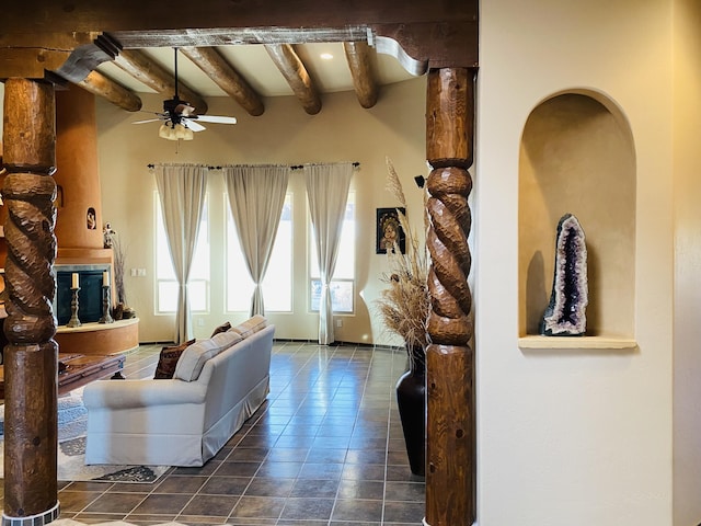 living area featuring beam ceiling, tile patterned floors, and a ceiling fan