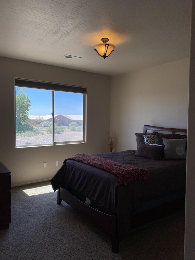 bedroom with carpet, visible vents, and a textured ceiling