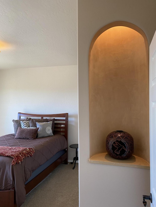 bedroom with arched walkways and carpet flooring