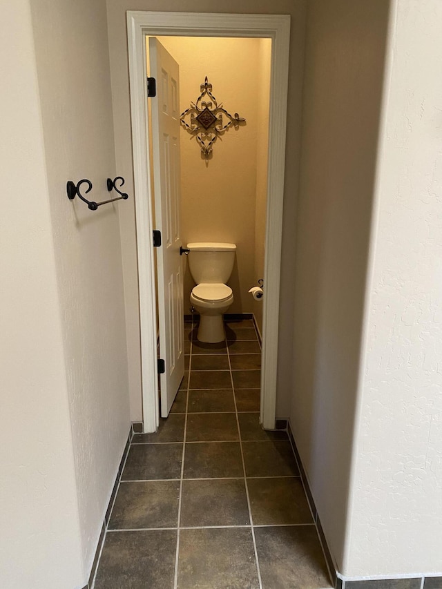 hallway with baseboards and dark tile patterned floors