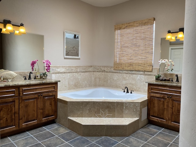 bathroom with two vanities, a bath, and a sink