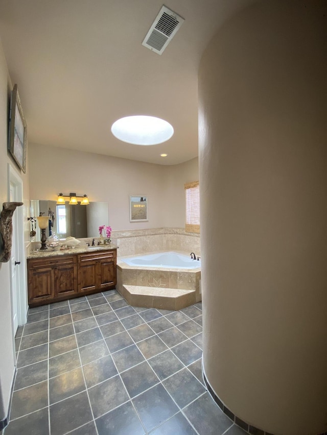 full bath featuring tile patterned floors, visible vents, a garden tub, and double vanity