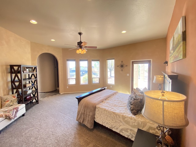 carpeted bedroom featuring recessed lighting, arched walkways, and ceiling fan