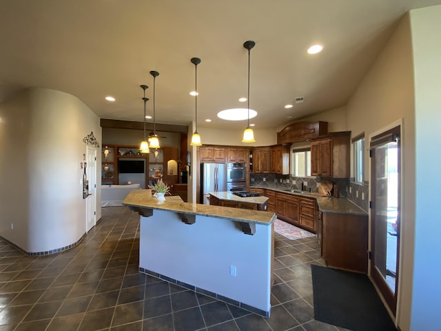 kitchen featuring dark tile patterned floors, a sink, a center island, appliances with stainless steel finishes, and decorative backsplash