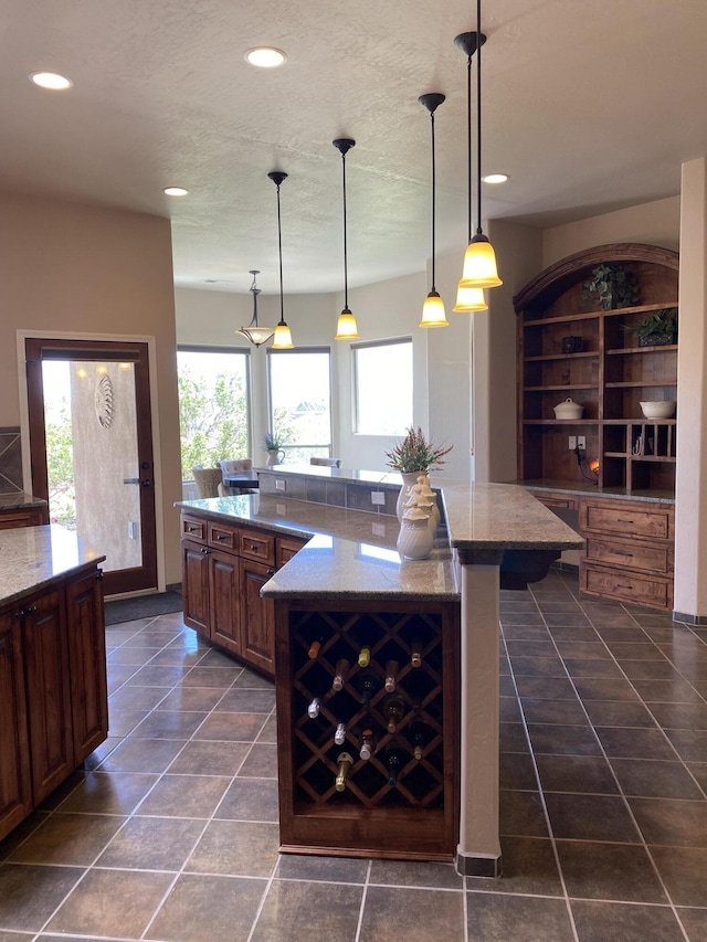 kitchen featuring recessed lighting, light stone countertops, a large island, and a breakfast bar