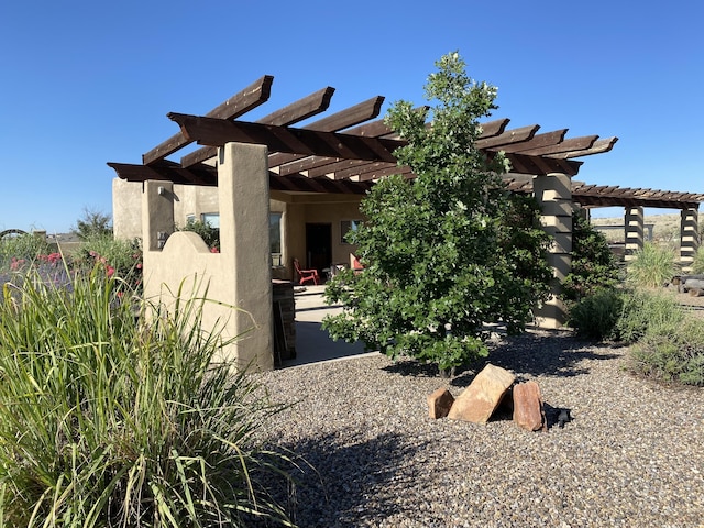 view of side of property featuring a patio area, stucco siding, and a pergola