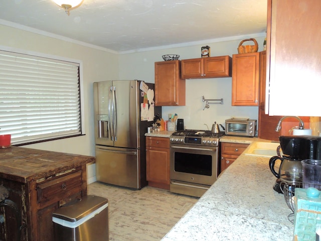 kitchen featuring brown cabinetry, a toaster, a sink, appliances with stainless steel finishes, and crown molding