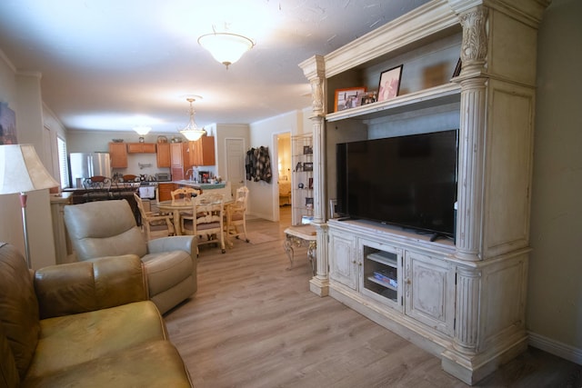 living area with baseboards, light wood finished floors, and ornamental molding