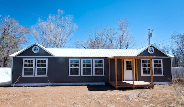 rear view of house with metal roof, a porch, and fence