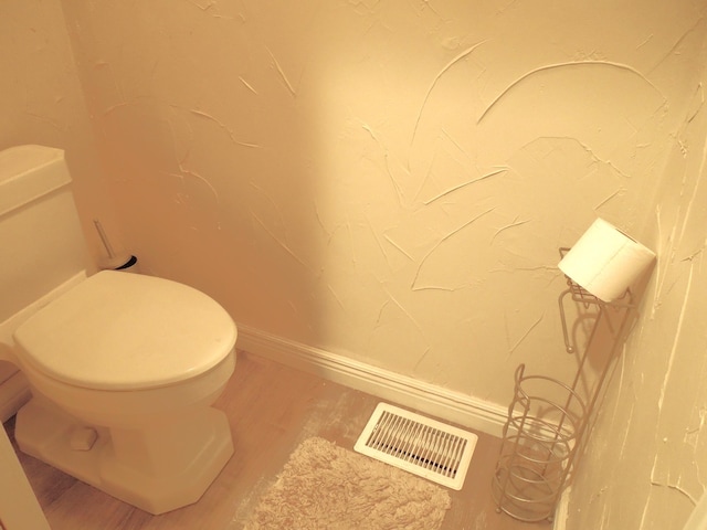 bathroom with wood finished floors, toilet, baseboards, and visible vents