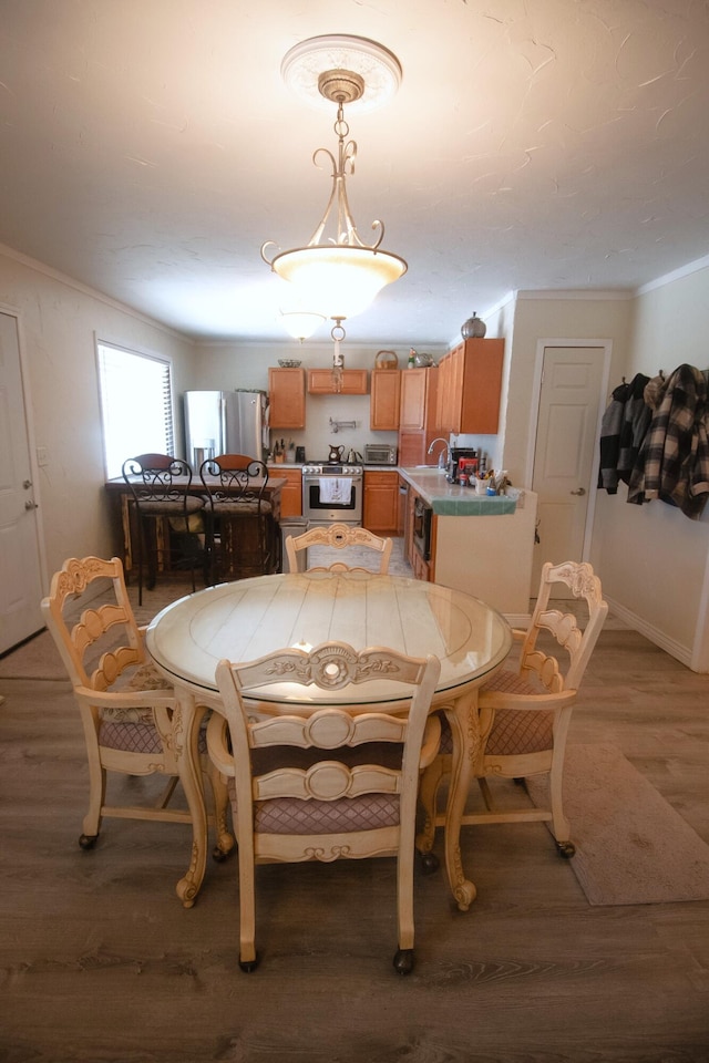 dining area with baseboards, light wood-type flooring, and ornamental molding